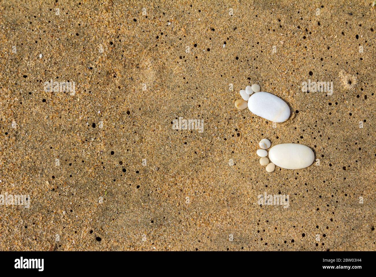 Passi di ghiaia su sabbia bagnata del mare, sfondo copyspace Foto Stock