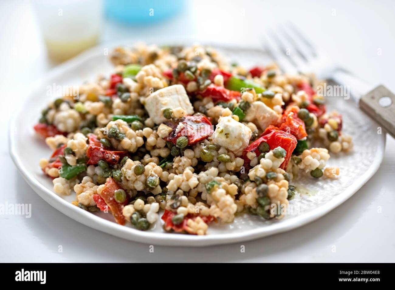 Insalata couscous gigante con formaggio feta, lenticchie, peperoni rossi e condimento vinaigrette Foto Stock