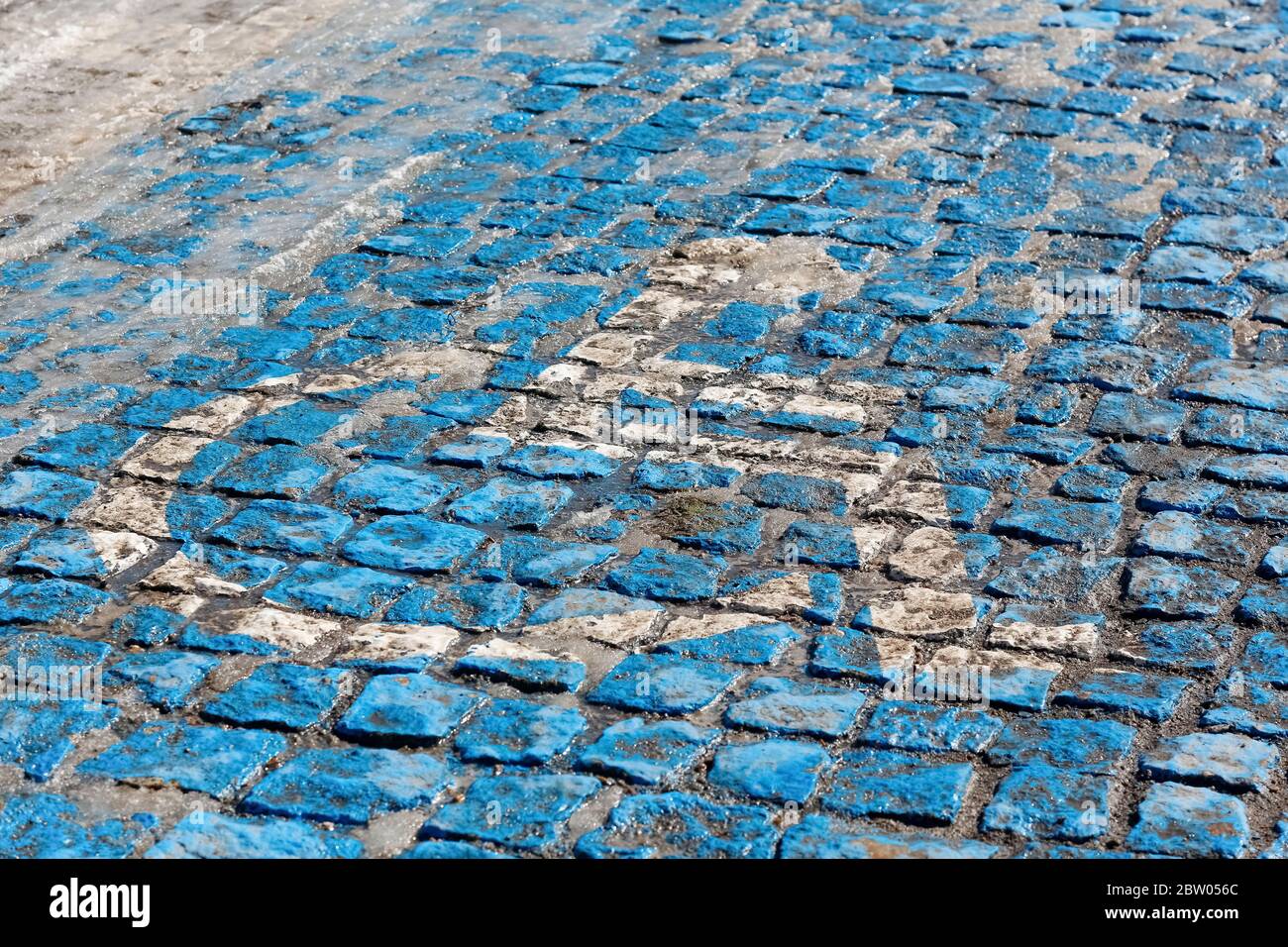 La sedia a rotelle che simboleggia lo spazio di parcheggio per disabili è stata dipinta in blu e bianco sulla superficie stradale acciottolata. Foto Stock