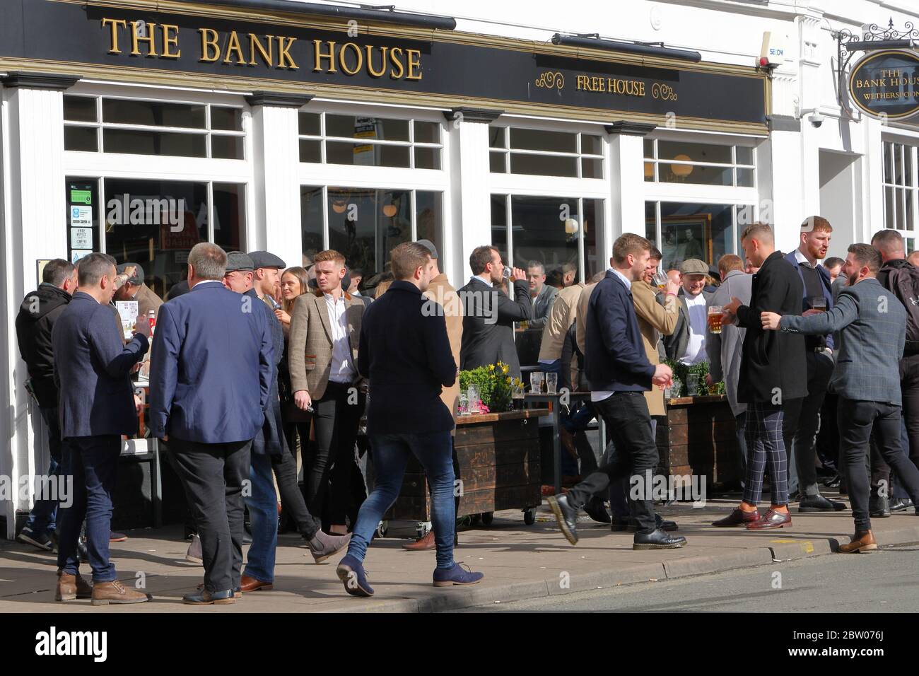 Un grande gruppo di persone che socializzano e bevono fuori dalla casa pubblica JD Wetherspoon la Bank House nel centro di Cheltenham Foto Stock