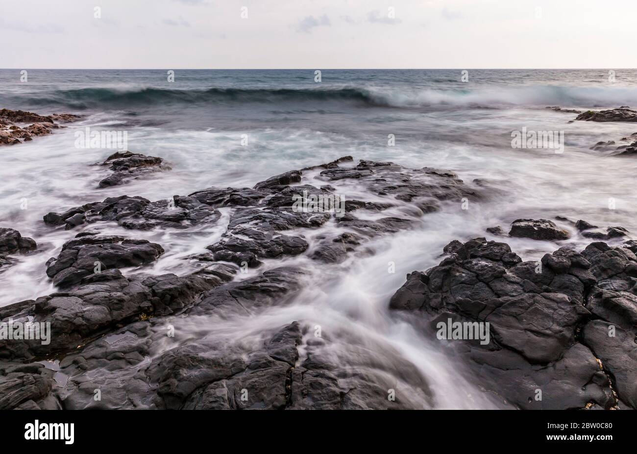 Il litorale roccioso e le onde infrangenti a Kailua-Kona, Hawai'i, Stati Uniti. Foto Stock