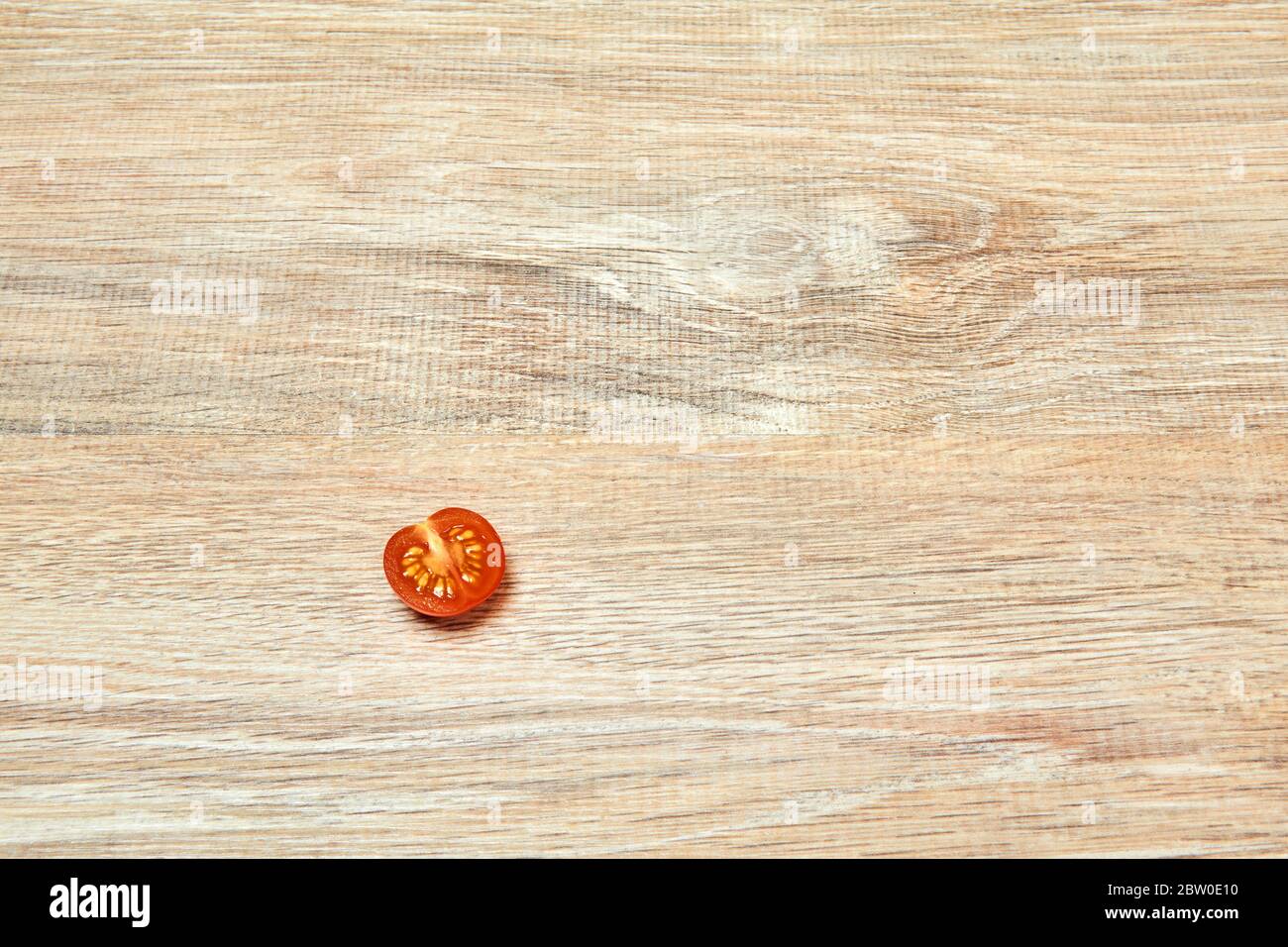 solo pomodoro a mezza ciliegia sul bordo di una superficie di tavola di legno Foto Stock