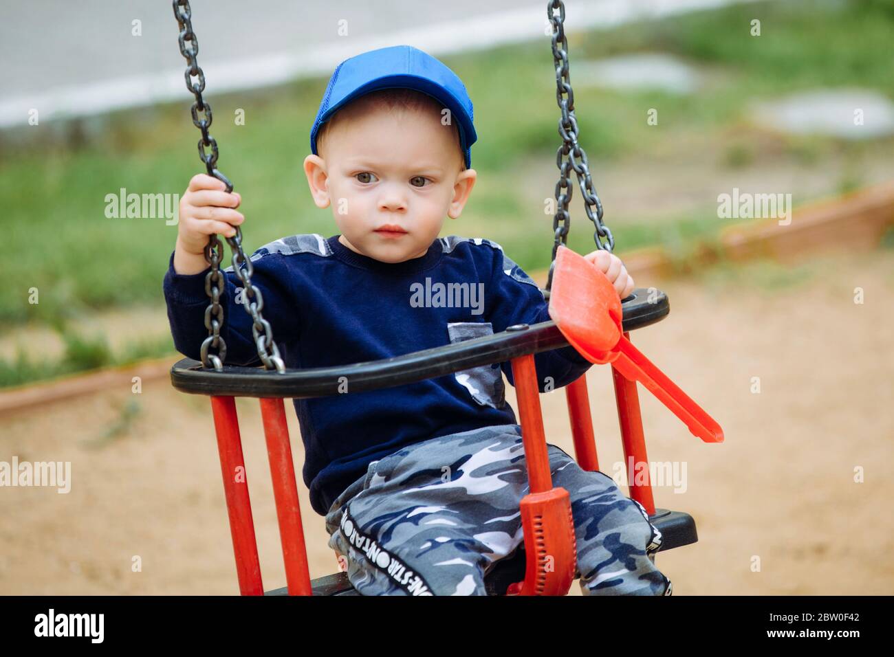 Bel bambino di 1-2 anni che cavalcano un'altalena e tiene i giocattoli nelle sue mani Foto Stock