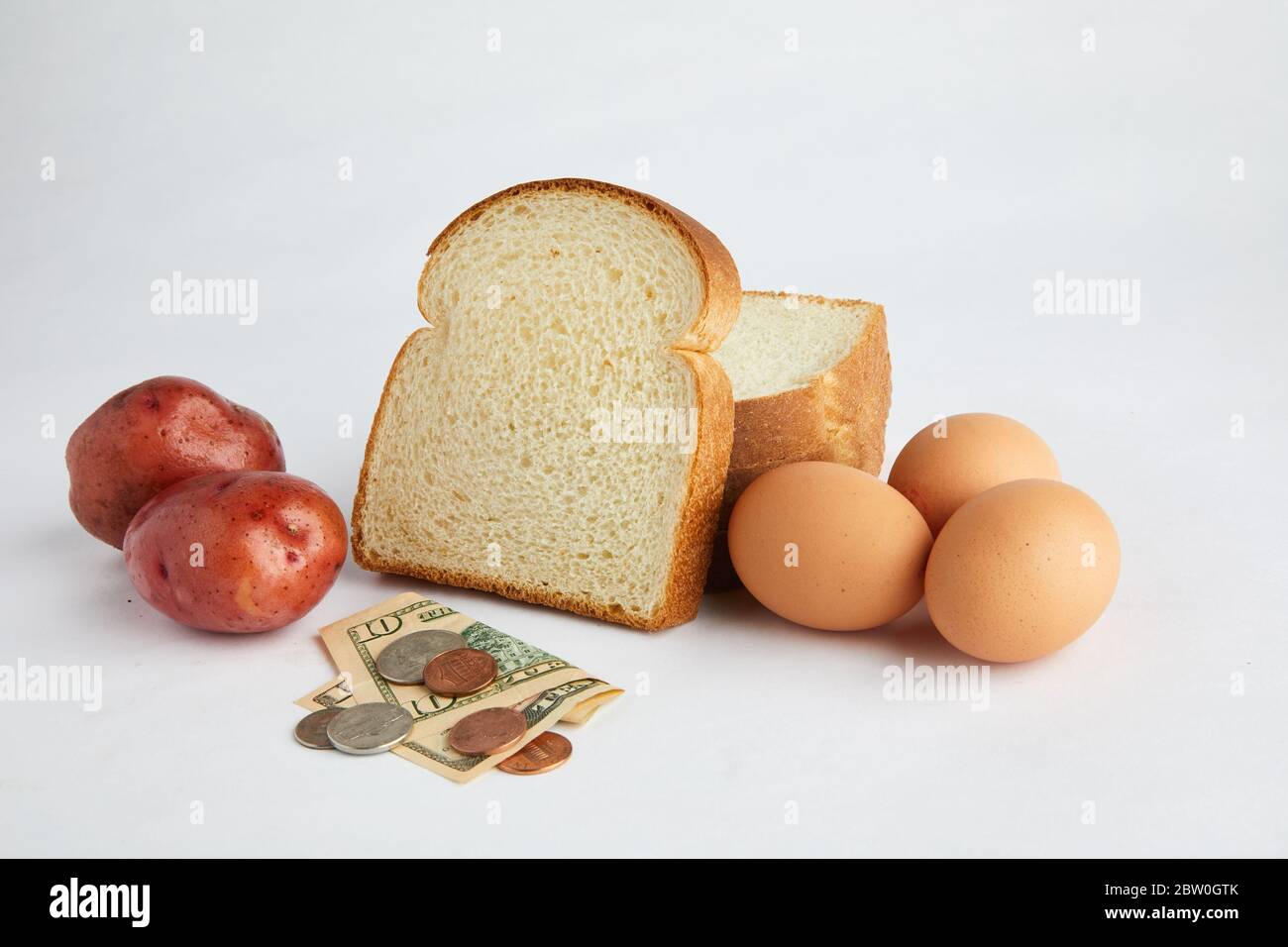 Studio di alimenti di base pane, uova e patate con valuta che illustra il costo del cibo e l'economia. Foto Stock