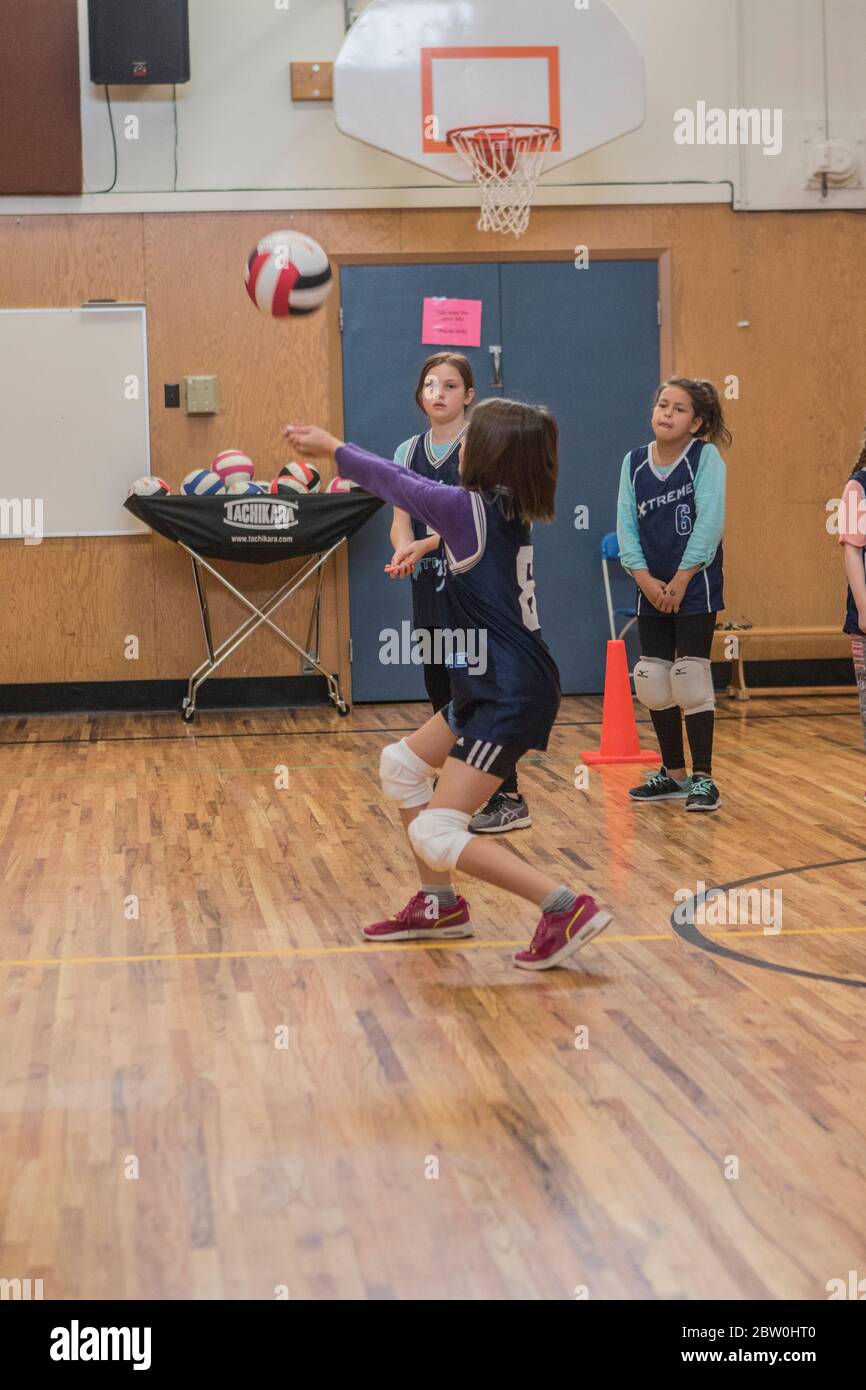 Ragazze volley-ball, 8 a 10 anni, accettando servire e cercando di impostare per il ritorno della palla. Foto Stock