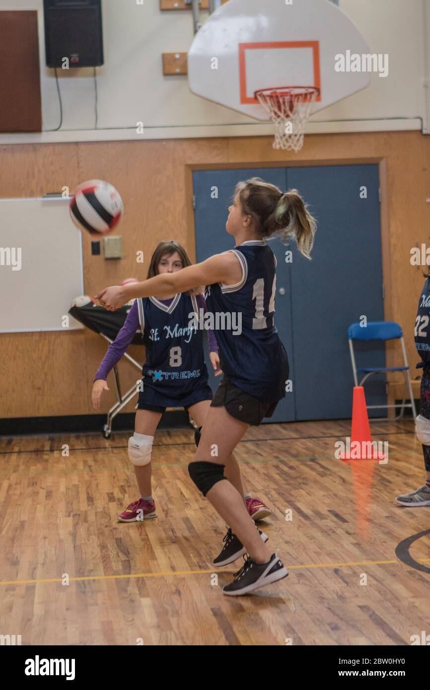 Ragazze volley-ball, 8 a 10 anni, accettando servire e cercando di impostare per il ritorno della palla. Foto Stock