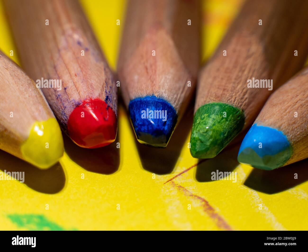 Primo piano di cinque matite colorate di giallo, rosso, blu, verde e azzurro dei miei figli su un foglio giallo Foto Stock