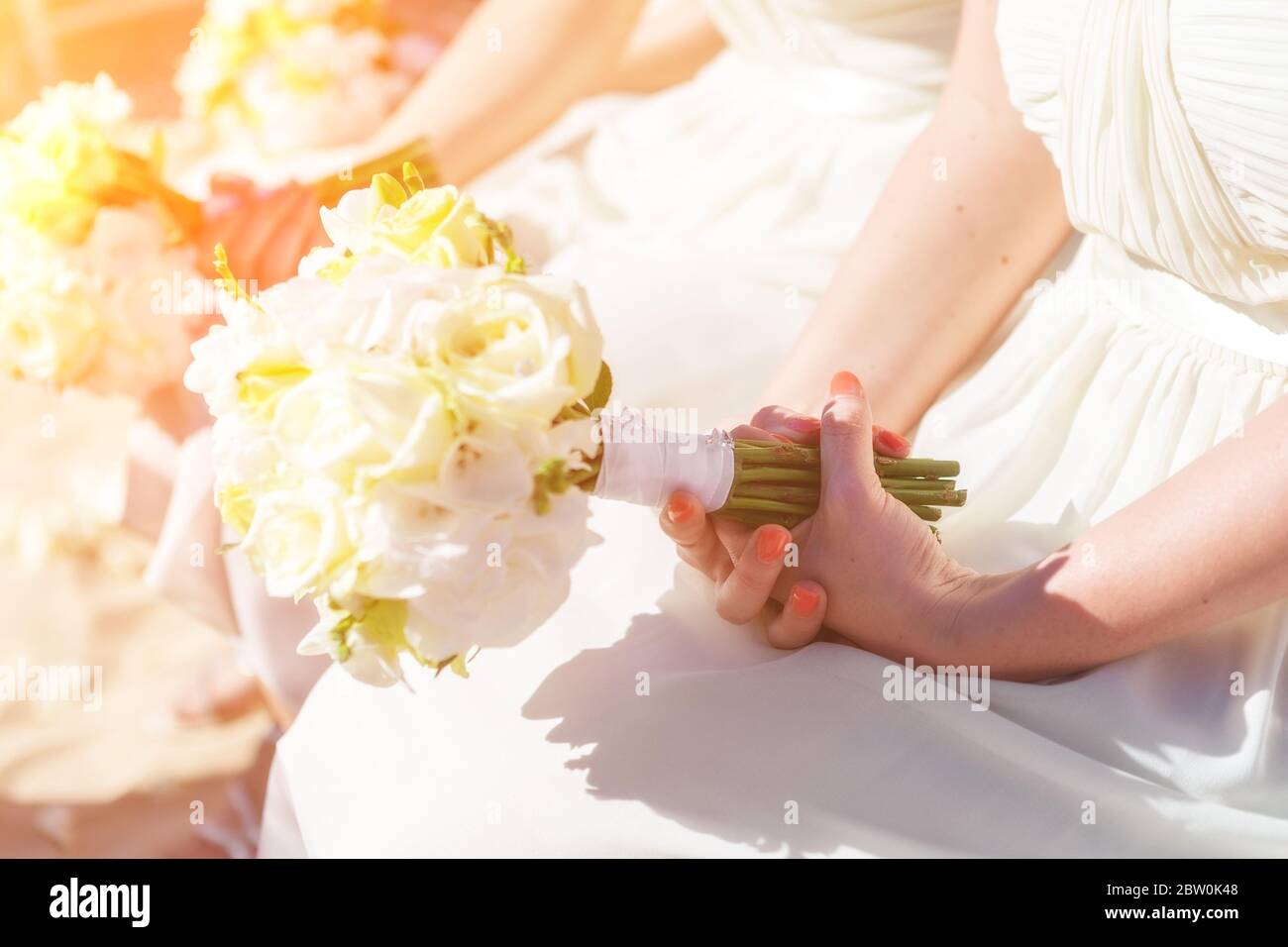 Sposi al matrimonio, in una giornata di sole, con un bel bouquet di fiori nelle loro mani. Foto Stock