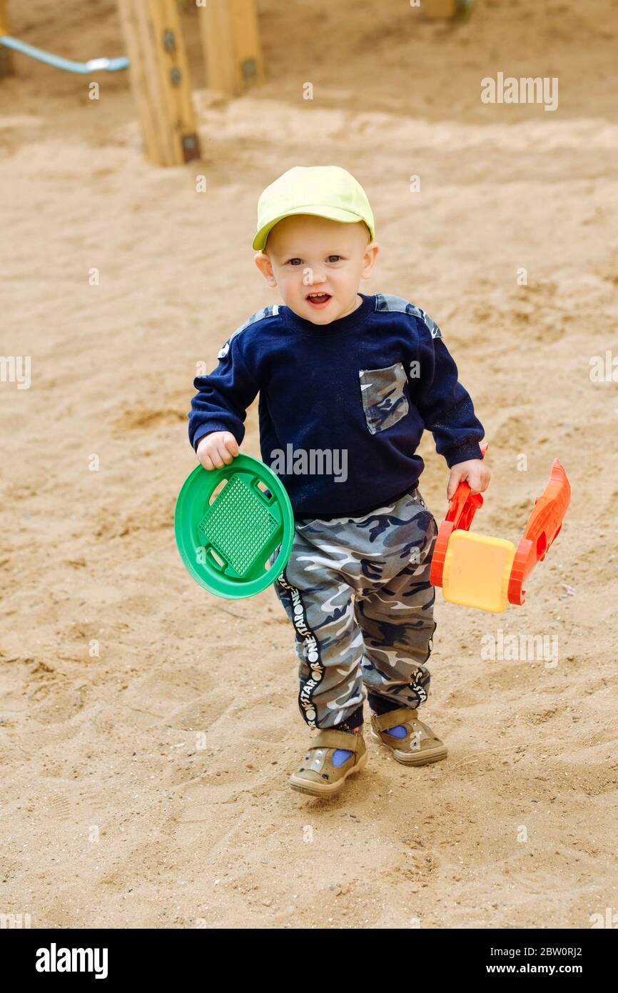 Un ragazzo gioioso di 1-2 anni gioca nel parco giochi con giocattoli Foto Stock