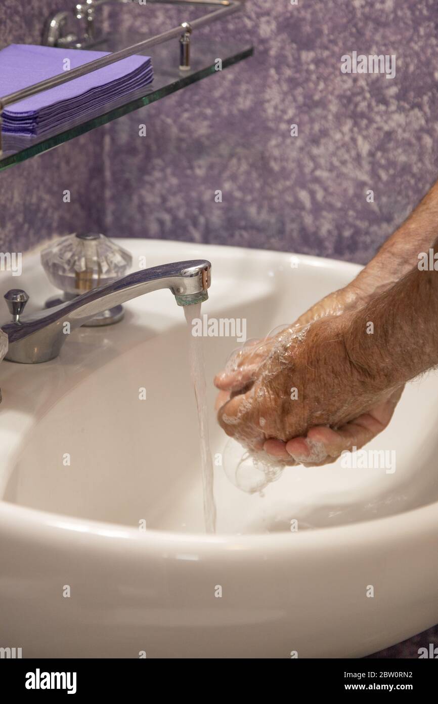 Mani che si immergono nel lavandino del bagno Foto Stock