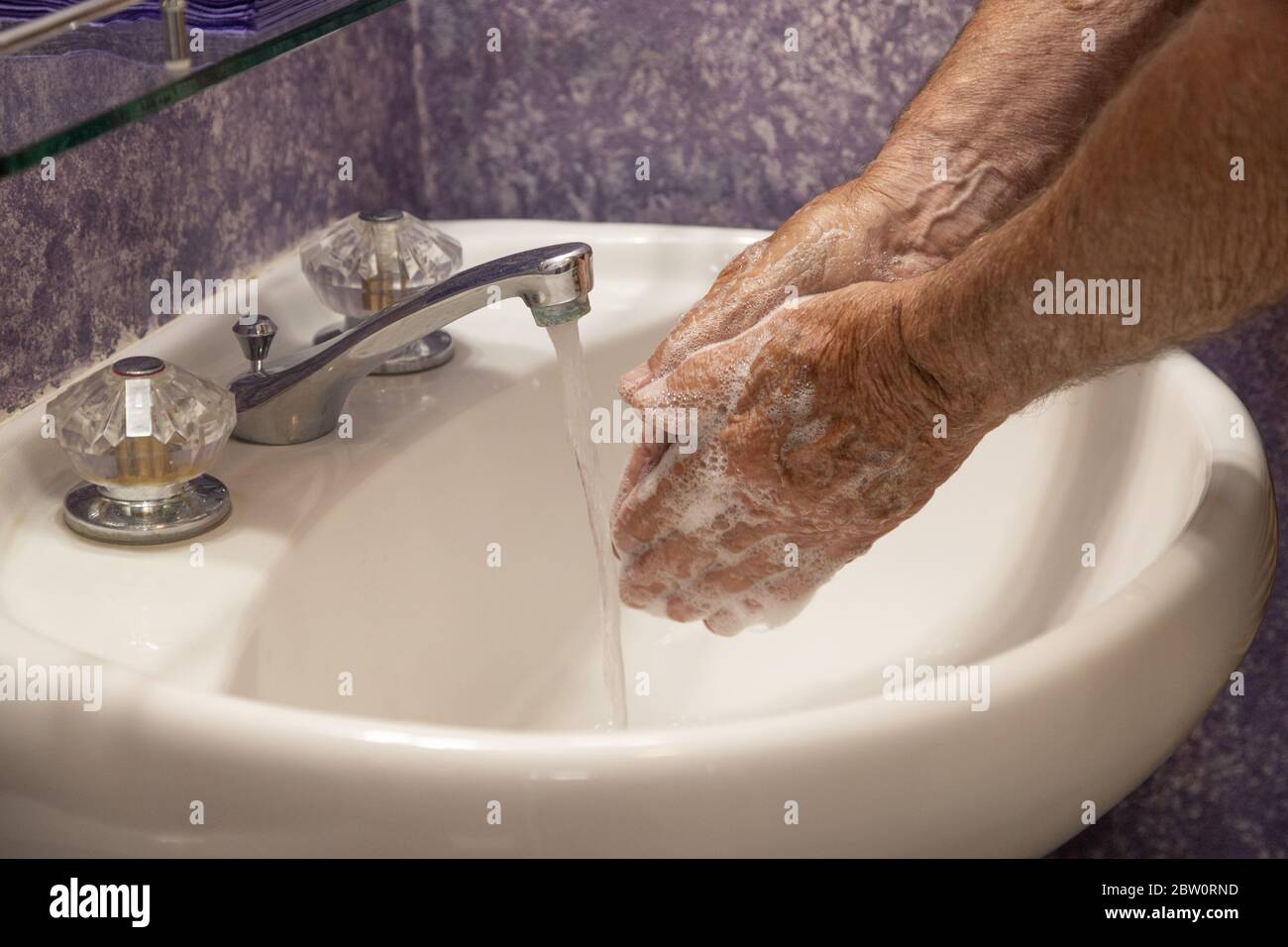 Mani che si insaporono con il lavello del bagno dell'acqua corrente Foto Stock