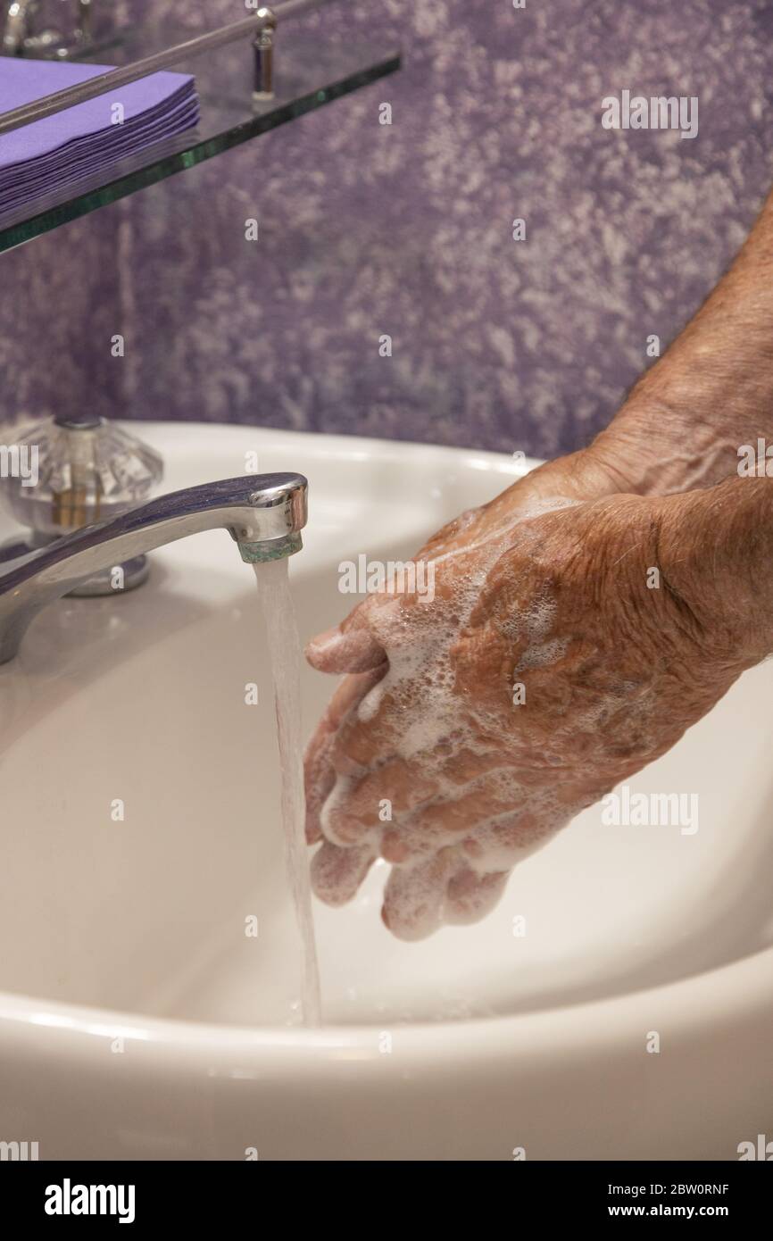 Mani che si insaporono con lavello verticale del bagno dell'acqua corrente Foto Stock