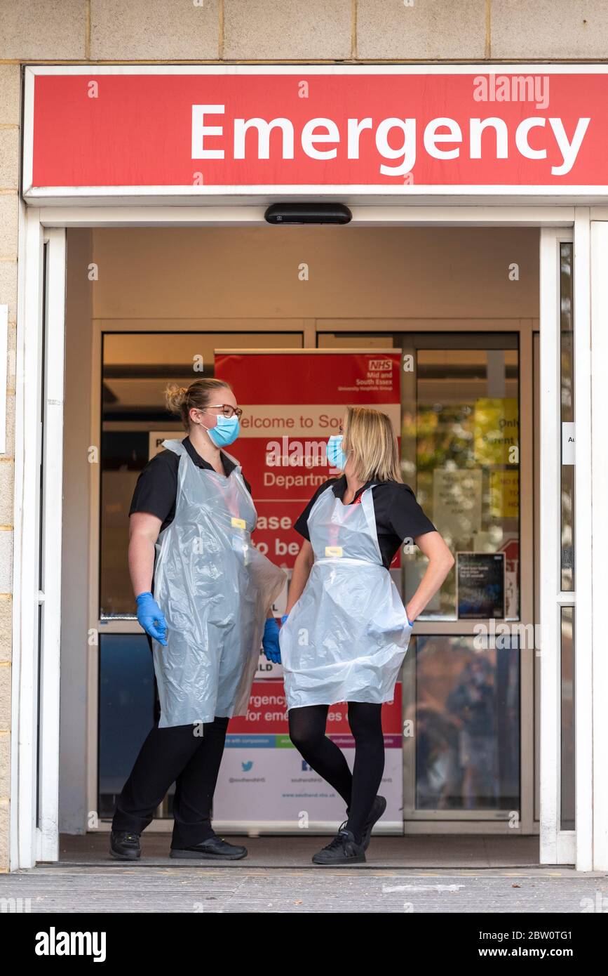 Personale sanitario all'ingresso del Dipartimento di emergenza presso il Southend University Hospital, Essex, Regno Unito. Due infermieri in DPI di base con maschere chirurgiche per il viso. COVID-19 Foto Stock
