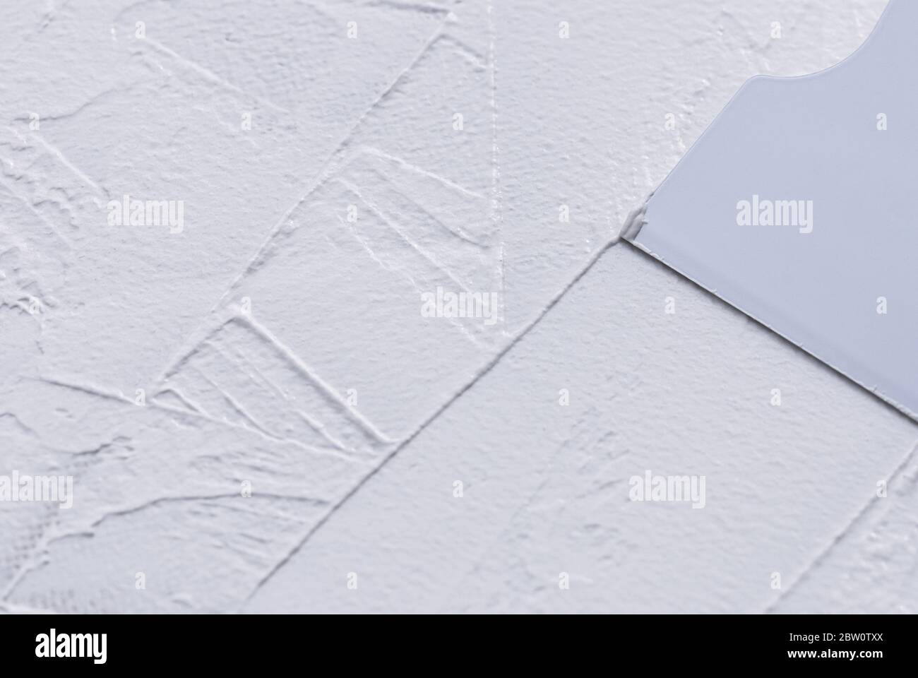 stendimento di stucco bianco con spatola in plastica, primo piano Foto Stock