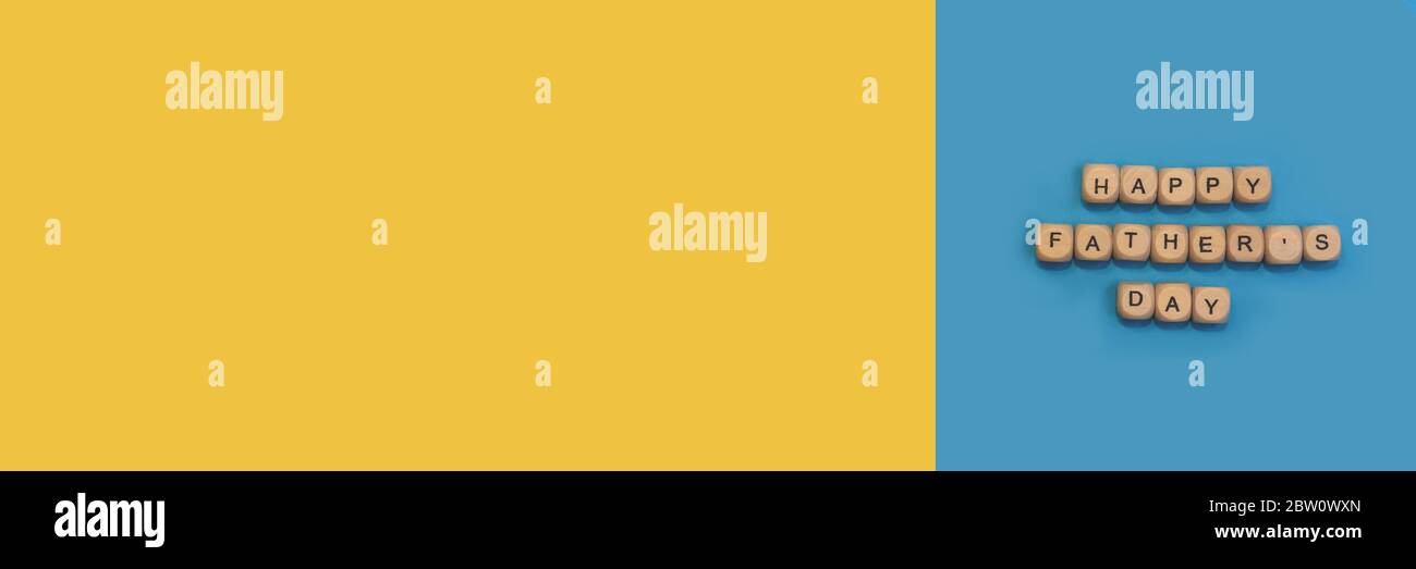 Un segno Happy Father's Day da blocchi di legno su sfondo blu e giallo. Concetto di festa del Padre. Foto Stock