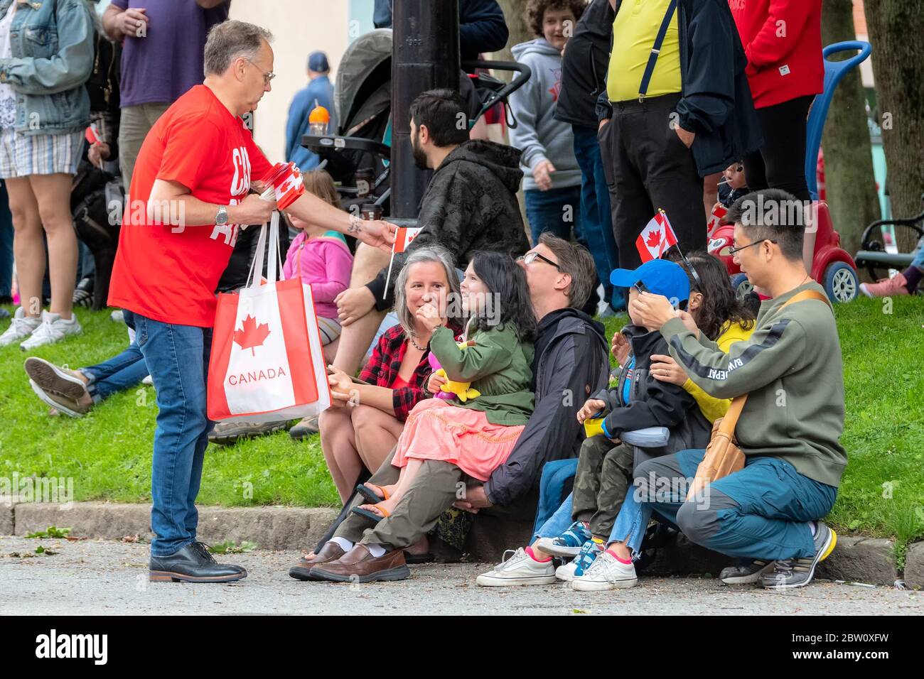 Saint John, New Brunswick, Canada - 1 luglio 2019: Gli immigrati che trasportano Canada, New Brunswick e altre bandiere partecipano alla sfilata del Canada Day. Foto Stock