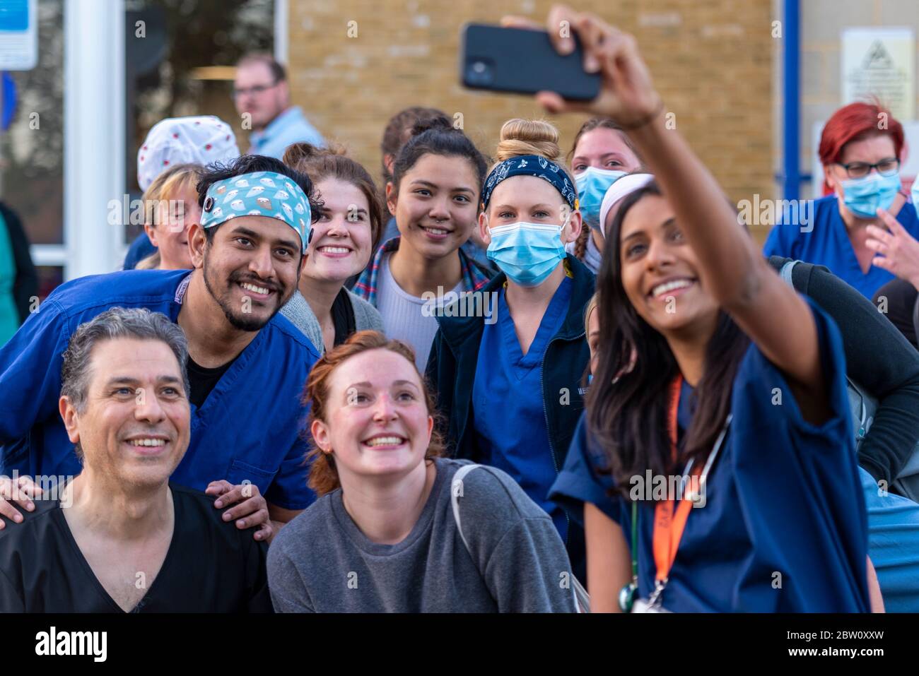 Personale al clap finale per gli accompagnatori alle 20:00 Giovedi fuori Southend University Hospital, Essex, UK. Gruppo di rione che si riunisce per un selfie. Medici e infermieri Foto Stock