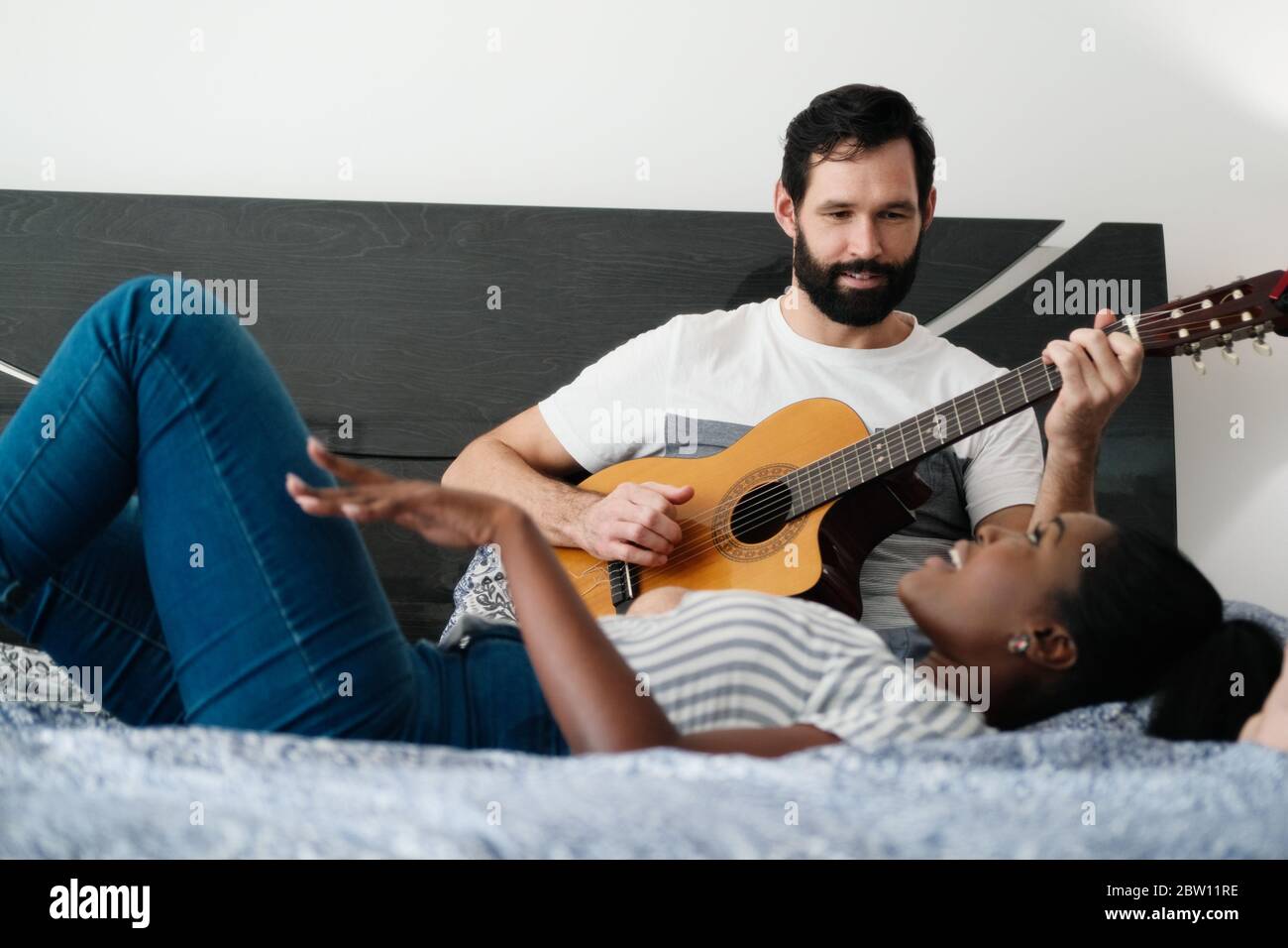 Uomo che gioca chitarra e canzone di canto della donna in camera da letto Foto Stock