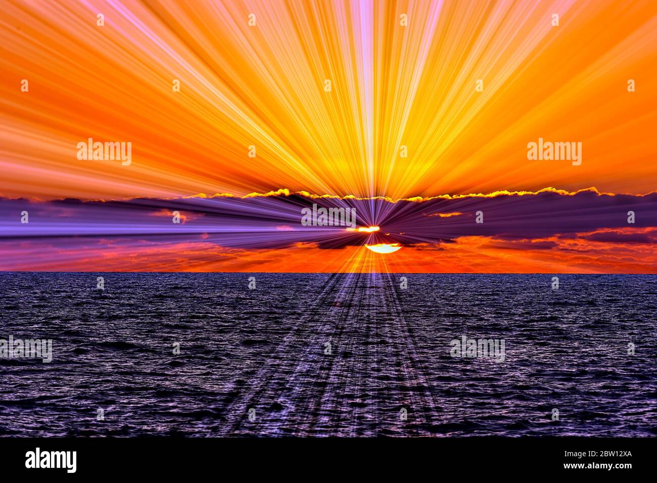 I raggi di luce stanno rompendo attraverso le nuvole come un tramonto arancione luminoso è nello sfondo Foto Stock