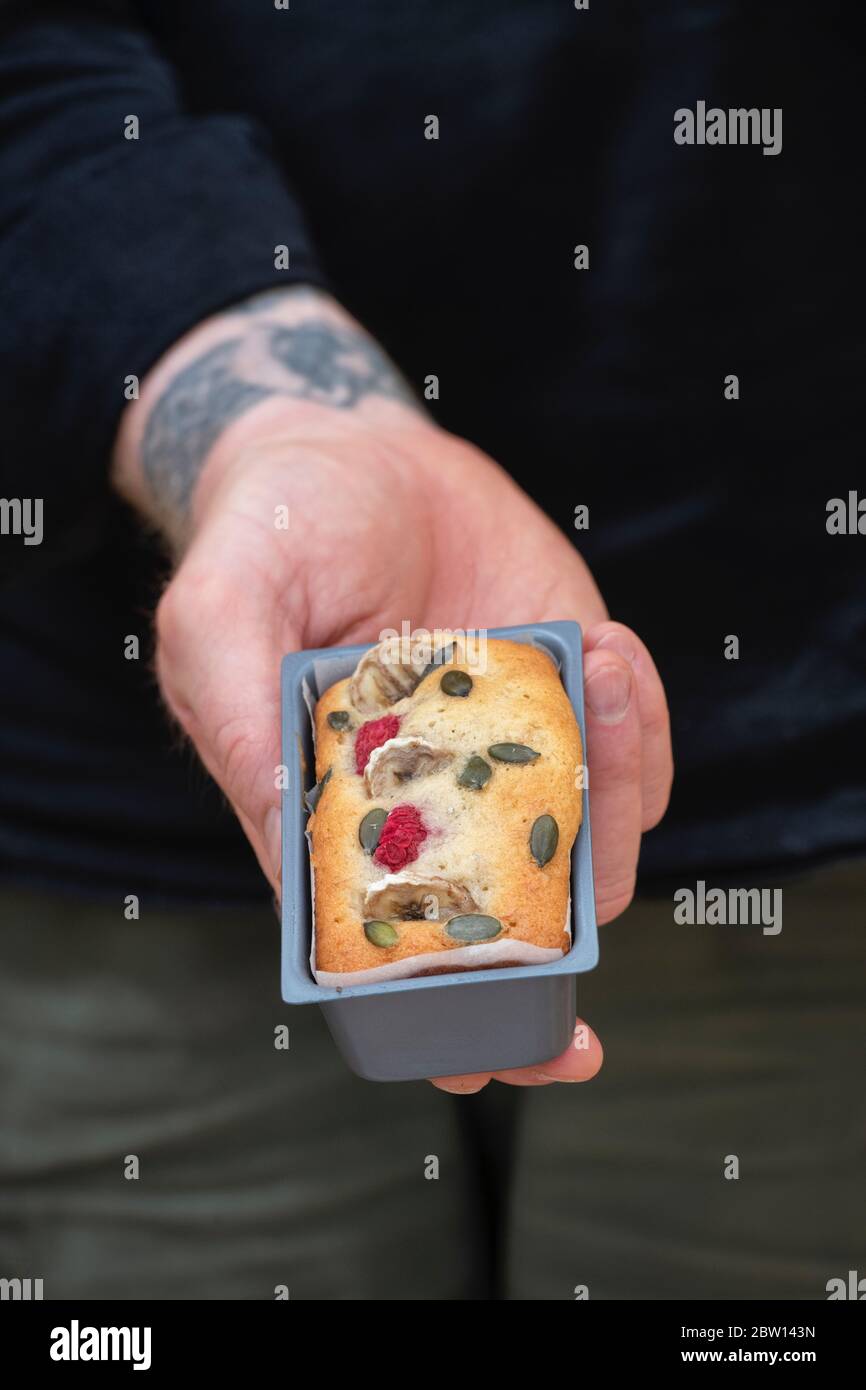 Uomo che tiene una mini banana e torta di lampone in una scatola Foto Stock