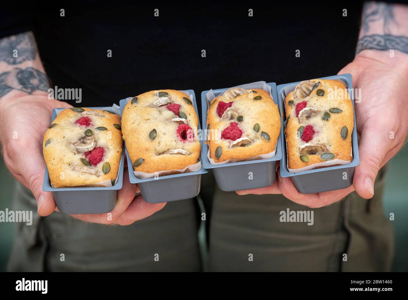 Uomo che tiene in casa mini banana e lampone torte in pagnotta Foto Stock