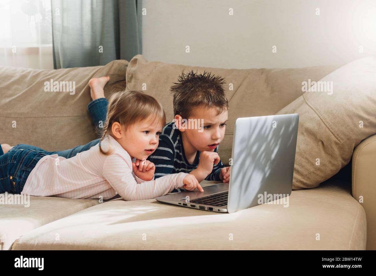 Bambini che studiano a casa usando lezioni online su computer portatile. Bambini che guardano i cartoni animati online. Quarantena a casa. Formazione online per i bambini. Foto Stock