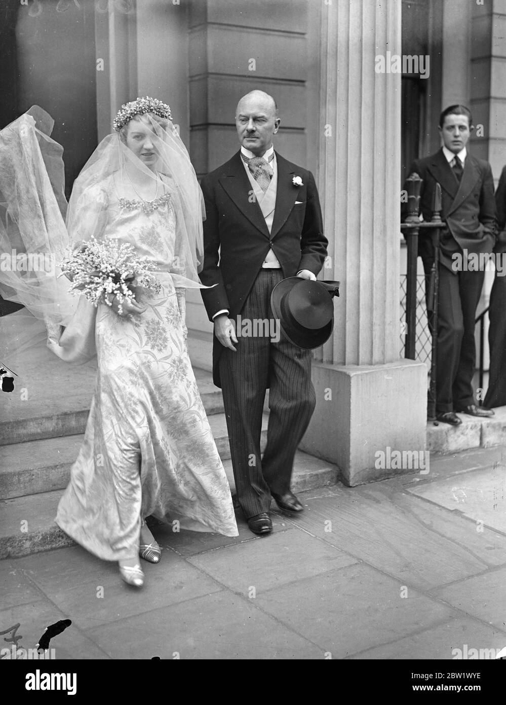 Lady Sylvia Maitland si sposò con Lord Carew a St Margaret's. Lady Sylvia Maitland, unica figlia del conte e contessa di Lauderdale, si sposò alla chiesa di St Margaret, a Westminster, con Lord Carew, il duca di Fanteria leggera della Cornovaglia. La sposa indossava una abito di broccato d'oro e seguiva dodici bridesmaid che indossavano camici di morbido materiale bianco rifiniti con ceneri d'oro per adattarsi all'abito della sposa. [Sposato contemporaneamente al Duca di Windsor. Londra Wedding rush.] Foto: Lady Sylvia Maitland lascia la sua casa, a 7 Grossenor Crescent Crescent, per la chiesa con suo padre, la e Foto Stock