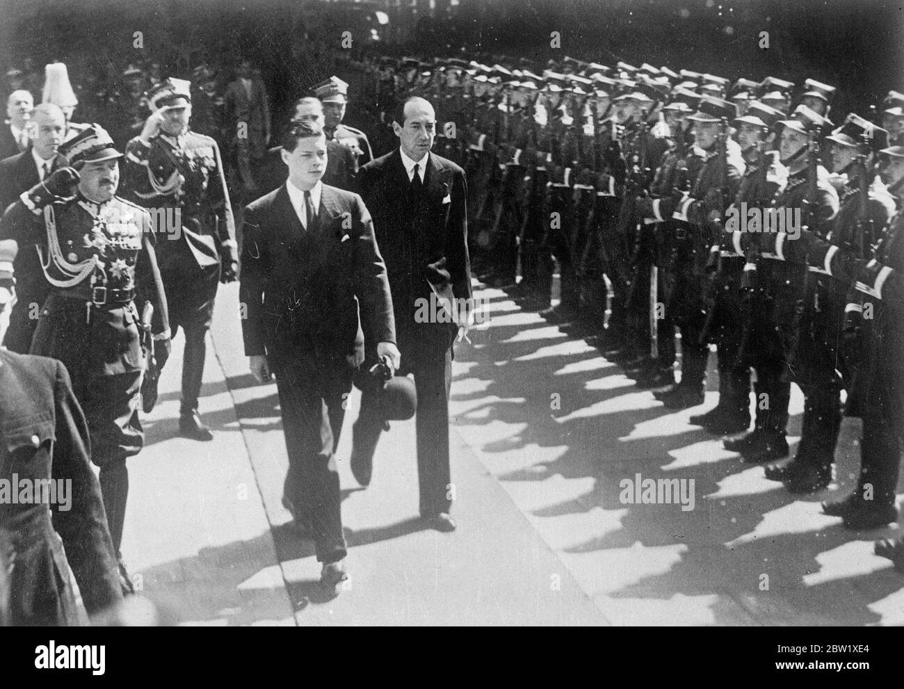 Il principe ereditario Michael arrivò a Varsavia senza i suoi vestiti. Senza tutti i suoi abiti, tranne quelli in cui aveva viaggiato - un abito da salotto scuro e scarpe marroni - il principe ereditario Michele di Romania è arrivato a Varsavia per trascorrere due giorni come ospite del presidente Moscicki del Polland. Alcuni bagagli personali del principe ereditario, contenenti le sue uniformi e abiti, erano stati collocati in modo errato alla frontiera belga-tedesca. La Legazione Rumena di Berlino ha dato istruzioni per spedirla immediatamente a Varsavia in aereo. Spettacoli fotografici: Il principe della corona Michael, in tuta da salotto, che riesamina la guardia d'onore in Wars Foto Stock