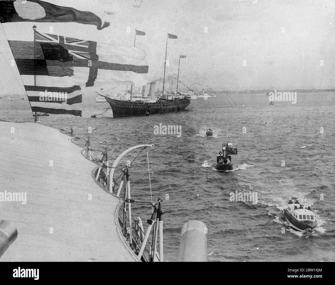 Re ispeziona l'ammiraglia della flotta dopo la revisione. Dopo la sua revisione della flotta il re visitò le varie bandiere degli squadroni e ispezionò gli uomini. Fu accompagnato dal Duca di Kent . Foto mostra, la Royal Barge (centro) che arriva a HMS Nelson HMS (numero del pennant 28) una nave da guerra di classe Nelson, dal Royal yacht 'Victoria and Albert' (sfondo) per la prima ispezione dei Re. 21 maggio 1937 Foto Stock