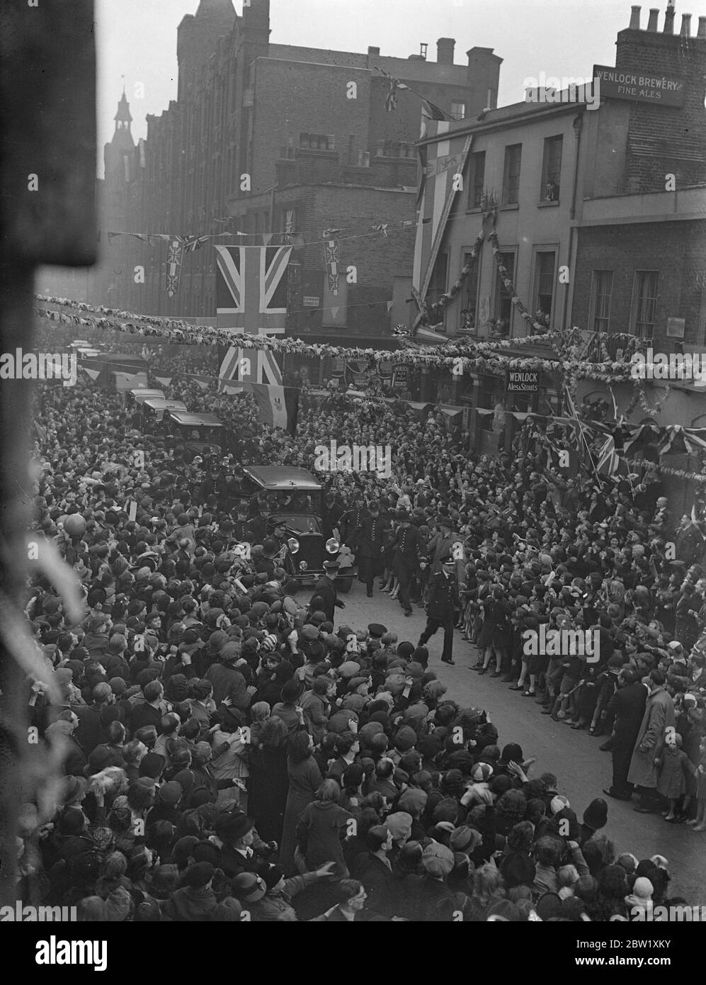 Modo della polizia per auto reale a Hoxton. Il giorno dopo la loro incoronazione, il Re e la Regina fecero un viaggio attraverso le strade decorate dei quartieri più poveri di Londra. Migliaia di persone si riunirono per salutarli e finirono in luoghi in cui la polizia doveva forzare la strada attraverso la folla per la Royal Car. Foto spettacoli: La polizia cerca di forzare un modo per la Royal auto attraverso la folla eccitato a Hoxton. 13 maggio 1937 Foto Stock