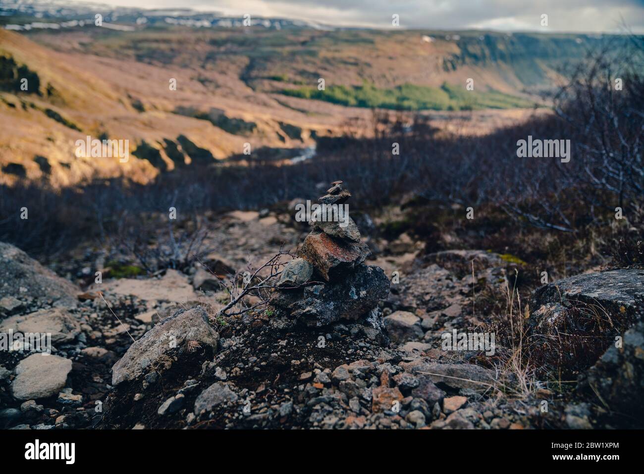 Rocce impilate in islandese paesaggistico con una valle coperta di sole sullo sfondo Foto Stock