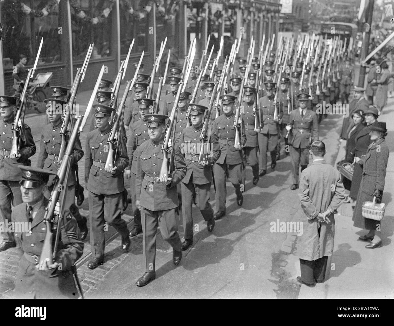 Ottenere gli uomini RAF abituati a fissare la folla per l'incoronazione. Il personale della Royal Air Force ha provato a Uxbridge per le mansioni del giorno dell'incoronazione. Guidati dalla loro band, marciarono lungo Uxbridge High Street per abituarli a fissare la folla. Spettacoli fotografici, gli uomini RAF marciano attraverso Uxbridge High Street. 6 maggio 1937 Foto Stock