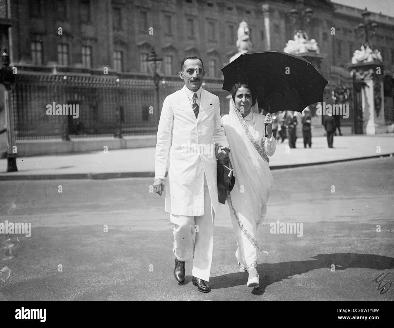 Un allarme Amber diventa un ombrello per proteggere sua moglie dal caldo sole di Londra, mentre Khan Sahib A C Jassawall lascia Buckingham Palace dopo aver ricevuto l'ISO dal re. 11. Giugno 1937 Foto Stock
