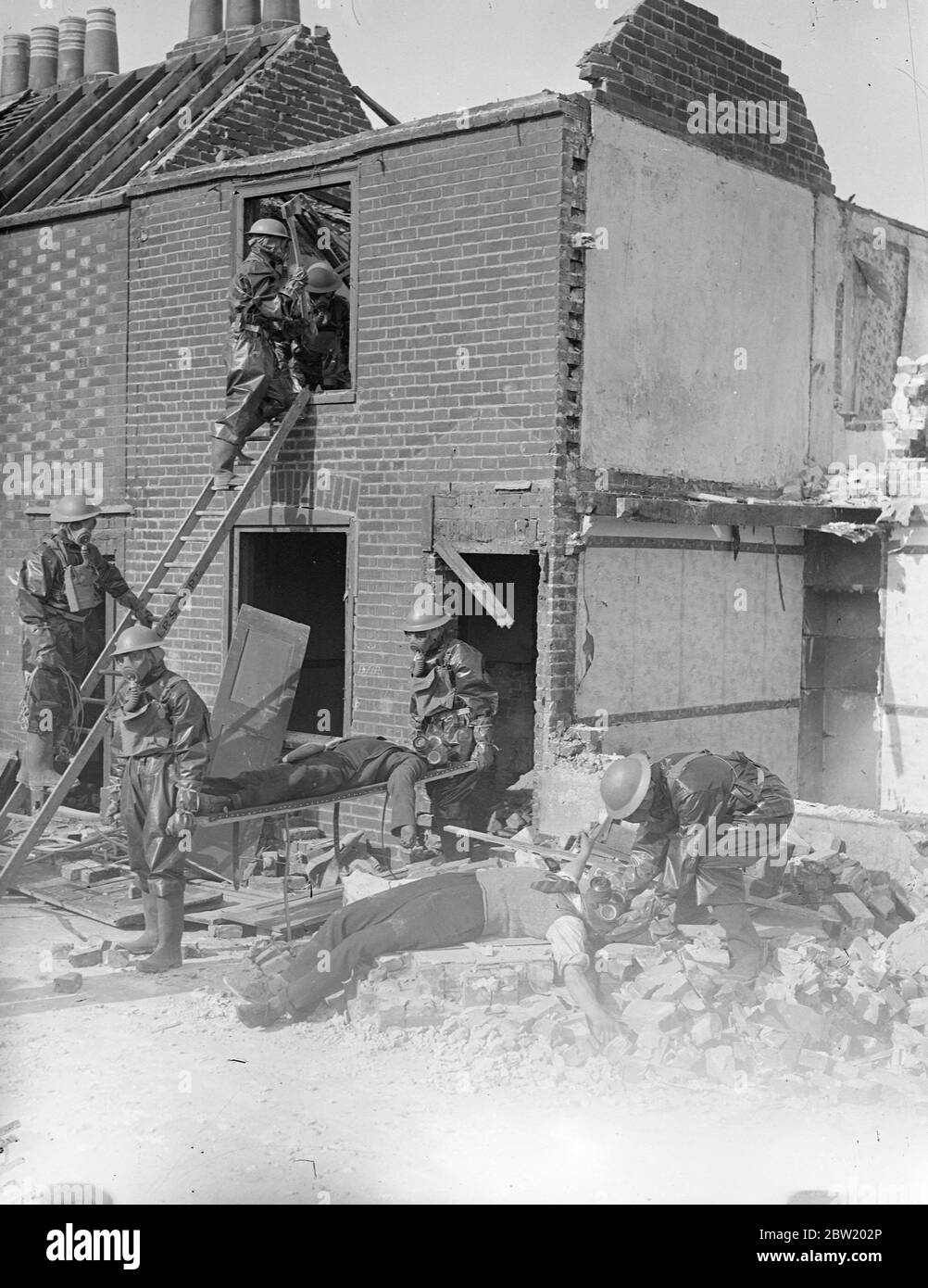 Le squadre anti raid indossate maschere a gas, le squadre di demolizione e salvataggio degli ingegneri della città di Portsmouth hanno pulito e decontaminato le rovine di edifici che sono stati bombardati dall'aria durante la battaglia simulata sulla costa meridionale tra l'esercito e la marina e l'aviazione. 14 luglio 1937 Foto Stock