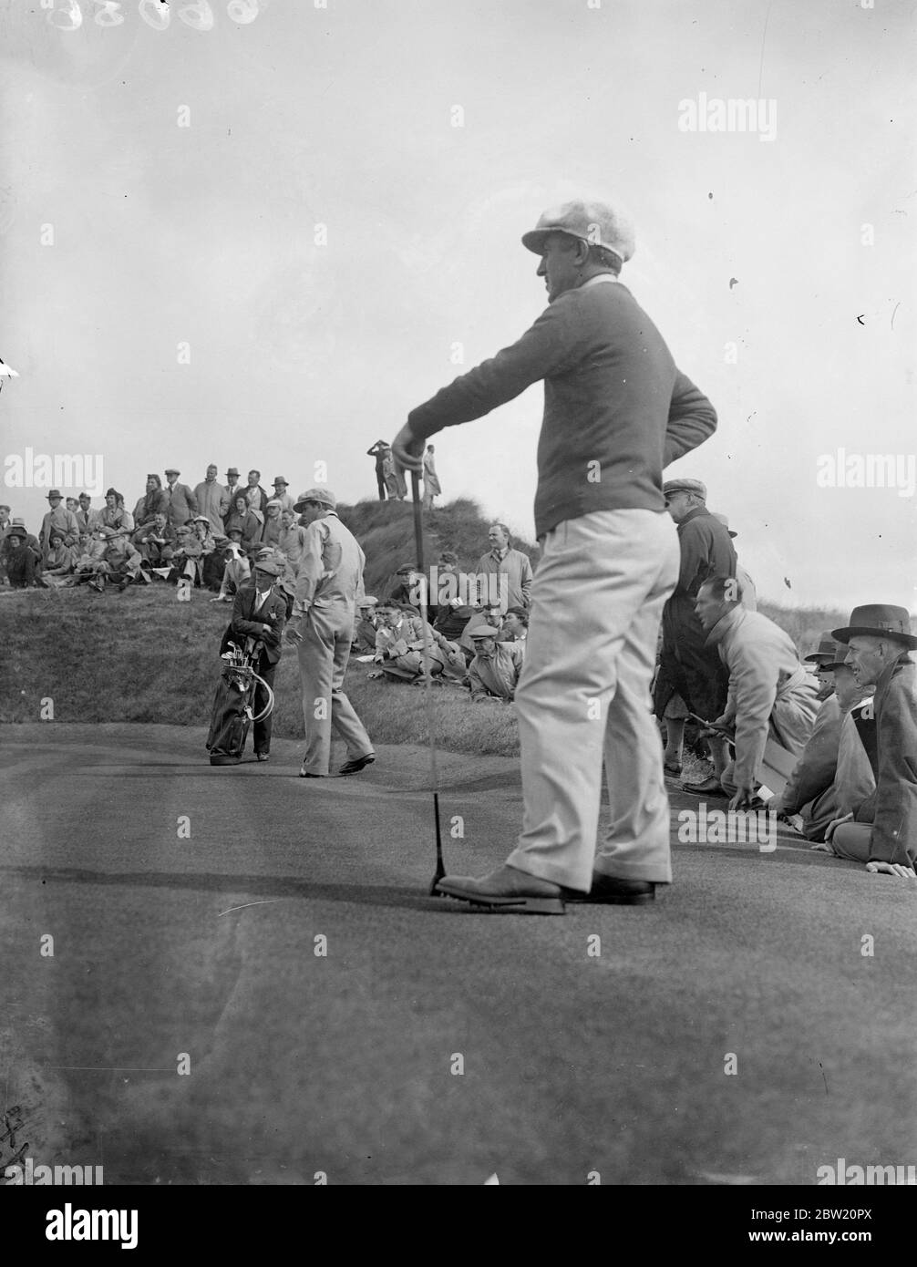 Le partite della Ryder Cup tra Gran Bretagna e America si sono aperte sul campo di Ainsdale a Southport, Lancashire. Ralph Guldahl mette sul secondo verde guardato dal suo compagno Tony Manero. Essi sconfissero A. J. Lacey e W. J. Cox d'Inghilterra 2 e 1. 29 giugno 1937 Foto Stock