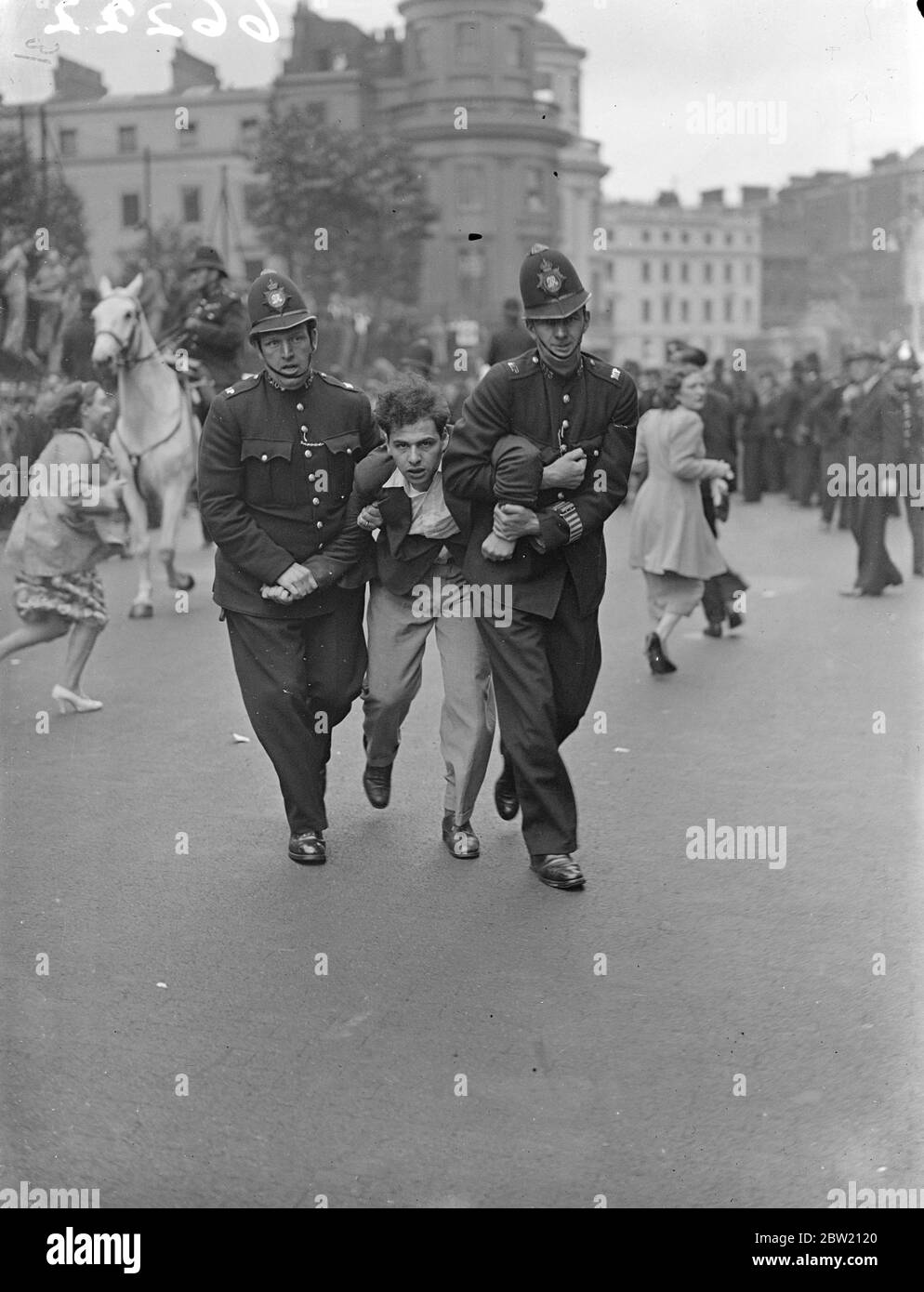 Dimostratore di arresto della polizia alla riunione di Trafalgar Square. Feroci combattimenti tra fascisti e loro avversari, scoppiarono in Trafalgar Square quando Sir Oswald Mosley, leader dell'Unione dei fascisti britannici, si rivolse ad un incontro dei suoi seguaci. Centinaia di forze di polizia erano pronte ad affrontare i disordini. Foto mostra, un dimostratore che è marciato via da due poliziotti. 4 luglio 1937 Foto Stock
