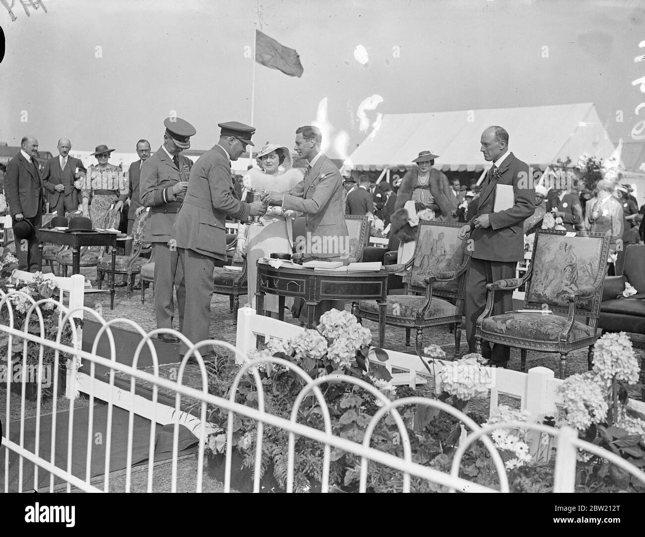 Il Re presenta la coppa al comandante dell'ala, D. V. Carnegie, vincitore dell'AFC (Ministero dell'aria) della gara della sede centrale. Il Re e la Regina hanno guardato l'annuale Royal Air Force Pageant all'Hendon Aerodrome. 26 giugno 1937 Foto Stock