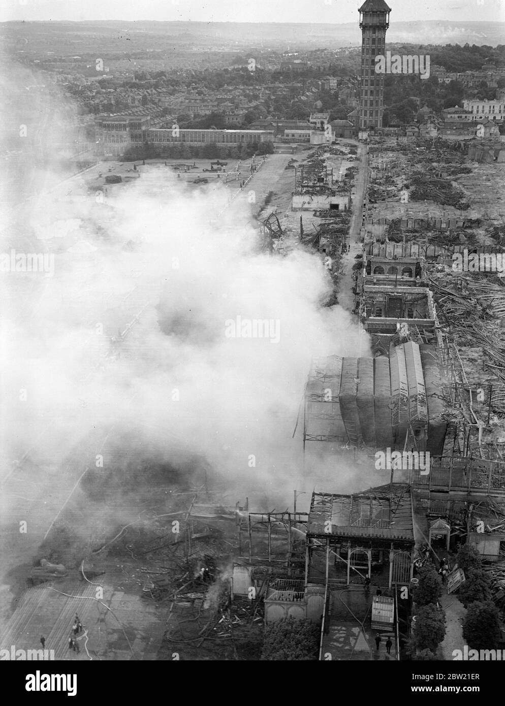 Il fumo che si alzava dal fuoco di Crystal Palace, visto per chilometri, scoppiò tra le rovine che si verificò nella vecchia Scuola d'Arte, biblioteca e pista di pattinaggio, che, a parte le torri nord e sud con solo porzioni lasciate in piedi dal grande incendio di novembre. 19 agosto 1937. Foto Stock