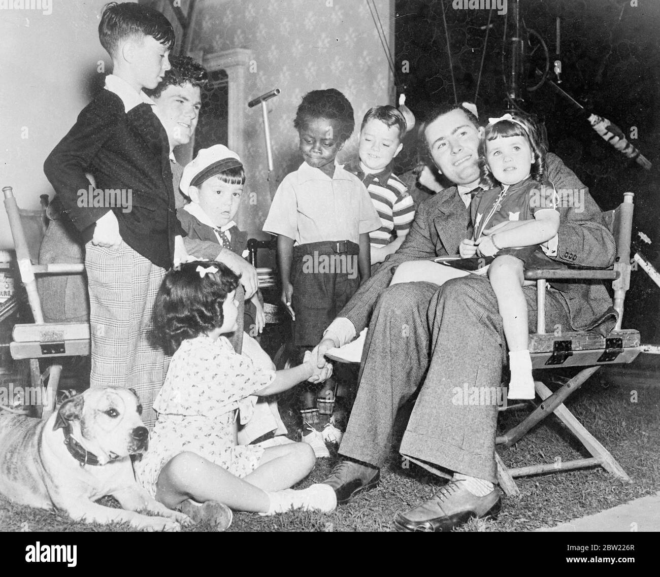 Vittorio Mussolini (a destra) con i membri della nostra banda agli studi Hal Roache di Hollywood. Victoria sta tenendo il bambino Patsy e sul pavimento R Peet, il cane, e Darla cappuccio. Victoria è a Hollywood per coinvolgere i registi tecnici a lavorare per la sua società cinematografica italiana in cui Hal Roache, il produttore americano delle nostre commedie di gruppo è associato. 6 ottobre 1937. Foto Stock