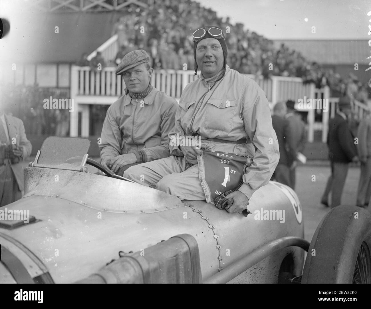 Con Sir Malcolm Campell come starter, la prima corsa di 500 km si è svolta a Brooklands, quando molti piloti ben noti hanno gareggiato. Negli anni precedenti, la gara ha superato una distanza di 500 miglia. John Cobb (in auto) stringendo le mani con il suo co-driver. Oliver Bertram, dopo la vittoria. 18 settembre 1937. Foto Stock