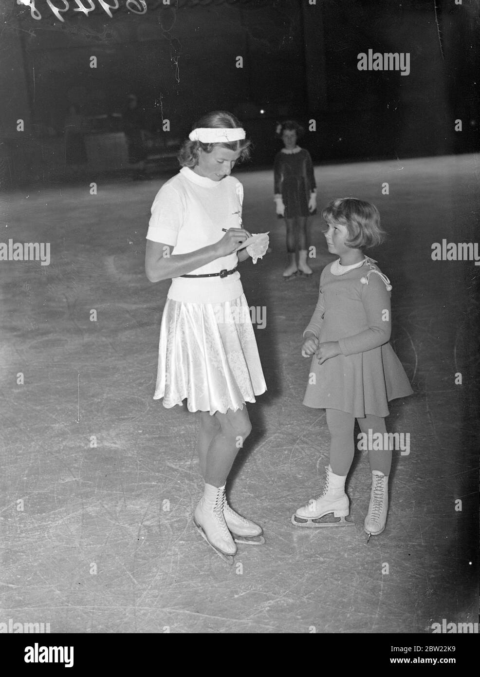 La più giovane pattinatrice svedese sul ghiaccio a Londra. Birthe Holmberg, sette anni, è arrivata a Londra ed ha già iniziato la sua mostra di pattinaggio presso il Queens Ice Club di Bayswater. Birthe era un medalista di bronzo a sei anni e cinque mesi. Spettacoli fotografici, Birthe Holmberg, di sette anni, che riceve l'autografo di Cecilia Colleedge, la campionessa mondiale di pattinaggio a figura del Queen's Club. 20 settembre 1937 Foto Stock