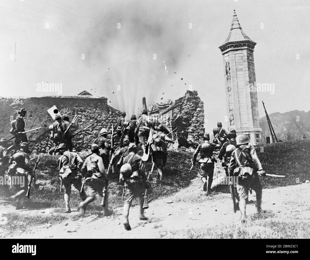 Le truppe giapponesi si spingono inesorabilmente in avanti mentre la loro gusci scoppiante si schiantano di muro nel loro percorso durante un attacco a Hankow, Cina del Nord. In questa zona si sono visti alcuni dei combattimenti più feroci delle ostilità sino-giapponesi. 15 settembre 1937. Foto Stock