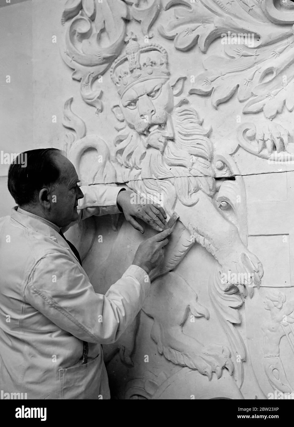 82 gli scudi araldici per il British Pavilion alla New York World Fair sono realizzati nello studio londinese di Gilbert Bayes, lo scultore. I disegni araldici sono stati verificati dal sig. Anthony Wagner, Portcullis Pursuivant al College of Arms. Foto: Gilbert Bayes (a destra) e un assistente al lavoro sullo scudo Oliver Cromwell per il padiglione britannico della New York World Fair nello studio di Londra MR Bayes. 12 ottobre 1938 Foto Stock