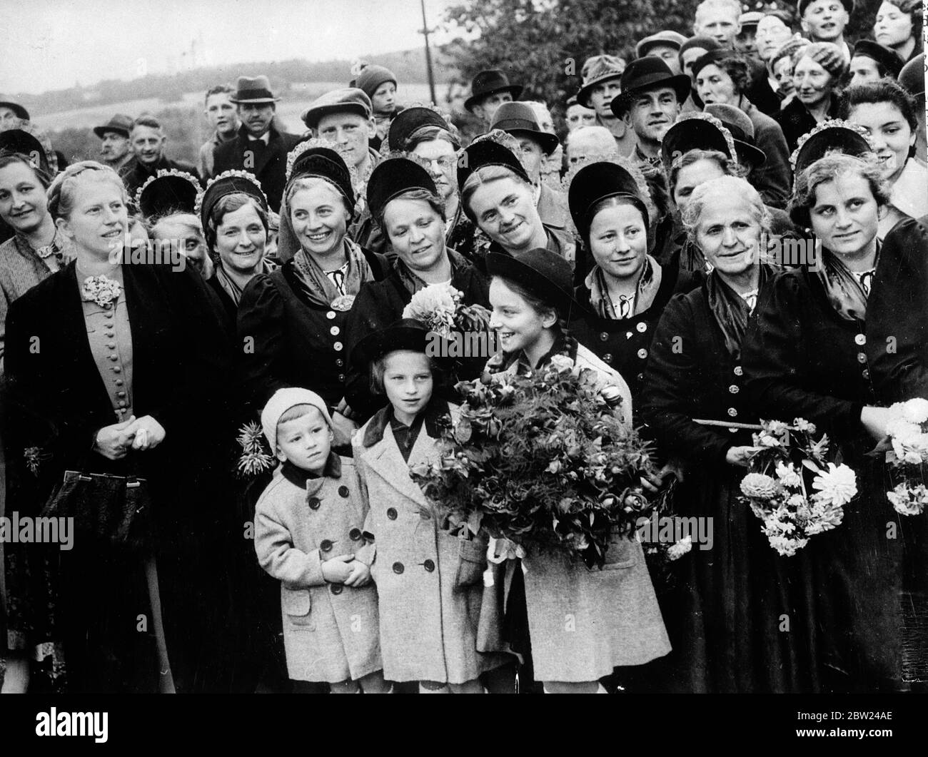 Frau Henlein e i suoi figli aspettano per la strada di salutare Hitler. Frau Henlein (a sinistra), moglie di Konrad Henlein leader del partito tedesco Sudetenland e ora commissario per il Sudetenland, aspettando con i suoi tre figli sulla strada vicino Wildenau di salutare Hitler quando ha fatto il suo viaggio trionfale attraverso il Sudetenland. Uno dei bambini sta tenendo un magnifico bouquet da presentare al Cancelliere. Dietro sono le ragazze Sudeten in costume nazionale. 4 ottobre 1938 Foto Stock