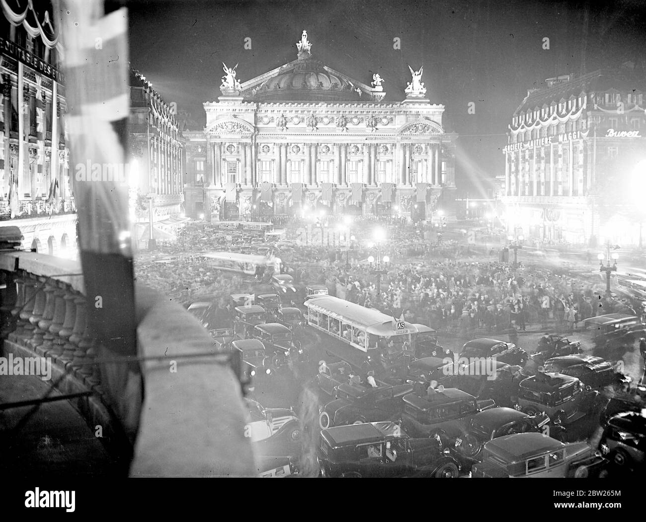 Parigi fa allegro tutta la notte, dopo l'arrivo di re e regina. Con la città una luce schiaffa, vaste folle riempirono le strade di Parigi fino all'alba, dopo l'arrivo a Parigi del Re e della Regina. Decine di potenti proiettori militari attraversano il cielo. Spettacoli fotografici, la vasta folla che riempie la luminosa Place de l'Opera. 21 luglio 1938 Foto Stock