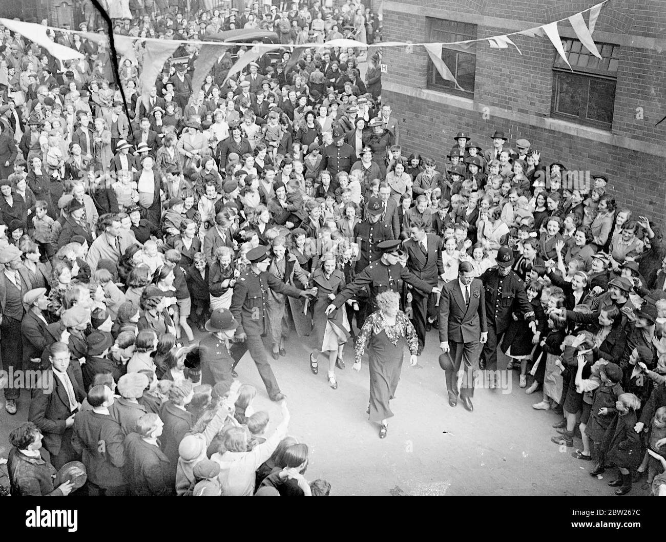 Duca di Kent visita l'insediamento di Battersea. Il Duca di Kent visitò il insediamento Katherine Low in High Street, Battersea. Foto mostra, il Duca di Kent seguito da una grande folla in Battersea High Street, mentre egli è andato da una parte dell'insediamento all'altra. 5 luglio 1938 Foto Stock