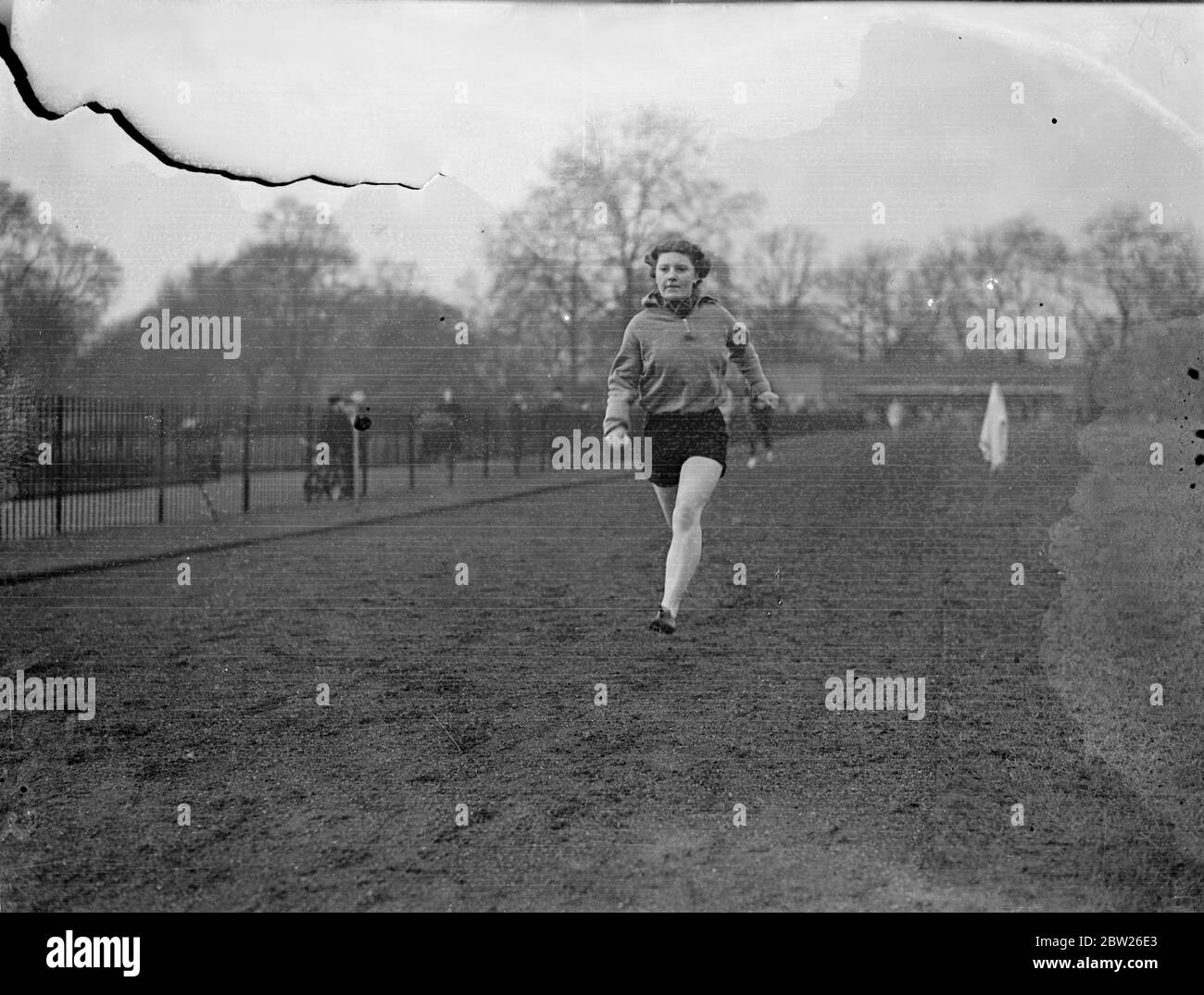 Business ragazza campione treni a Londra Park. Miss Ivy Bigwood, il campione delle Business Houses di Londra Four 1937, si sta allenando a Battersea Park, Londra, per i Campionati di atletica al coperto che si svolgono a Wembley in aprile. Padre la sta aiutando nella formazione. Mostre fotografiche, Miss Ivy Bigwood in una volata di allenamento intorno al circuito di Battersea Park. 1 febbraio 1938 Foto Stock