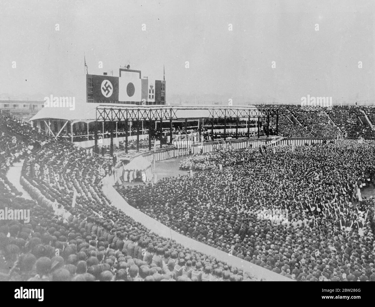 Bandiere dell'Alleanza su Tokyo riunione di massa del 80,000. Le bandiere di Italia, Germania e Giappone dominarono l'enorme stadio di baseball di Tokyo quando 80,000 studenti giapponesi e membri di gruppi giovanili hanno partecipato a un incontro di massa per esprimere il loro sostegno alla politica giapponese in Cina. Spettacoli fotografici, la swastika, il Sole nascente e la bandiera italiana sull'enorme incontro di massa a Tokyo. 11 gennaio 1938 Foto Stock