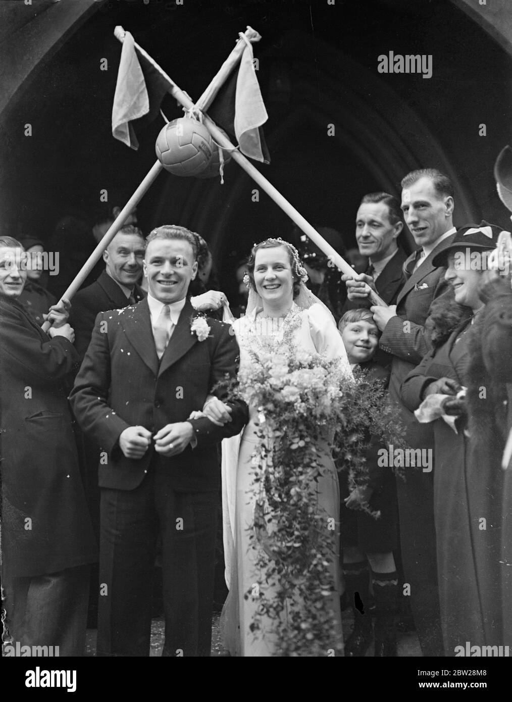 Arco di bandiere d'angolo per il calciatore Fulham e la sua sposa. Trevor Smith, il Fulham dentro a destra, è stato sposato con la signorina Lillian Boyce di Wimbledon alla Trinity Church, Wimbledon. Dopo la cerimonia, Smith si è rivelato per Fulham contro Plymouth Argyle a Craven cottage. Foto mostra, i bridegroomi che ha lasciato la chiesa con la sposa. 1 gennaio 1938 Foto Stock