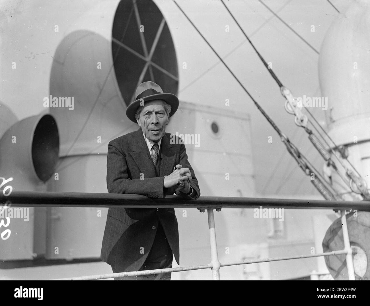 Monocled George Arliss torna a Hollywood. George Arliss, l'attore del film, completo di monotola, si appoggia sulla ferrovia di 'Aquitania' a Southampton al suo ritorno a Hollywood. 3 novembre 1937 Foto Stock